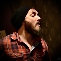a man with a beard is singing in a recording studio