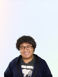 a young man with curly hair wearing glasses and a t - shirt