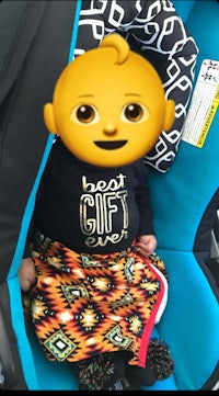 a baby in a car seat with an emoticon