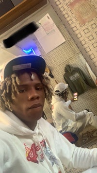 a man with dreadlocks in a white hoodie taking a selfie