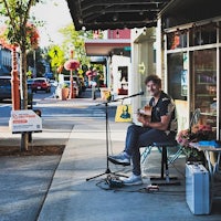 a man sits on a bench and plays an acoustic guitar