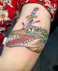 a tattoo of a crocodile with a sword on it