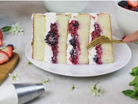 a slice of cake with berries and cream on a plate