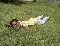a woman laying in the grass with a cell phone