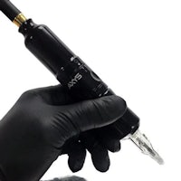 a hand holding a tattoo gun in black gloves