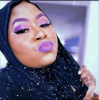 a woman wearing a black hijab and purple lipstick