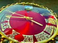 a gold plated watch with a red dial