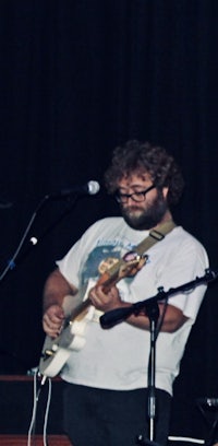 a man playing a guitar in front of a microphone