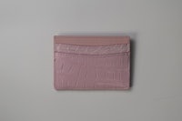 a pink crocodile wallet on a white surface