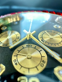 a close up of a watch with gold and red dials