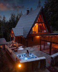 a cabin with a hot tub in the woods at night