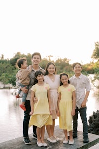 a family is posing on a dock in front of a river
