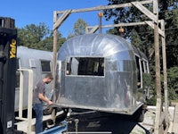 a man is working on a silver airstream trailer