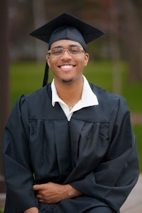 a man in a graduation gown sitting on a bench