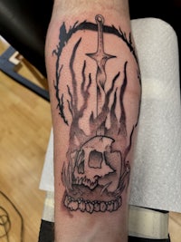 a tattoo of a sword and a skull on a man's forearm