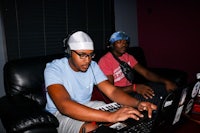 two men working on a laptop in a recording studio