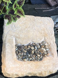a stone block sitting on a table with a plant on it