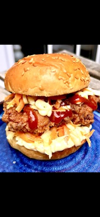 a chicken burger with ketchup and slaw on a blue plate