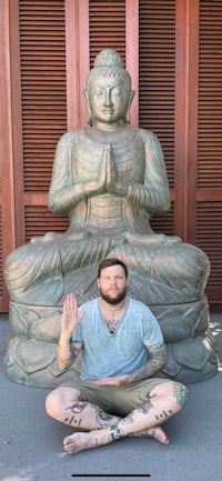 a man sitting in front of a buddha statue