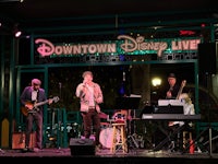 a group of musicians playing music in front of a sign that says downtown disney live