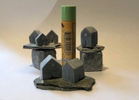 a set of small stone houses next to a bottle of paint