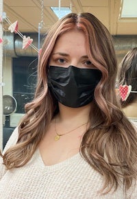 a woman wearing a black face mask in a salon