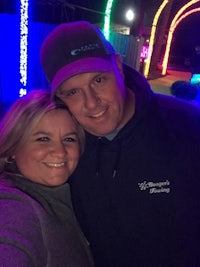 a man and woman posing for a selfie in front of a christmas light display