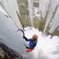 an ice climber is climbing up a cliff with icicles