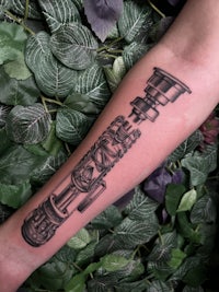 a tattoo of a telescope on the forearm
