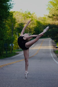 a girl is doing a ballet pose in the middle of a road