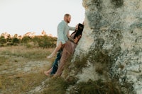 a couple leaning against a rock during their engagement session