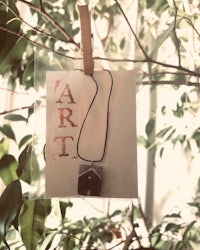 a necklace with the word art hanging from a tree