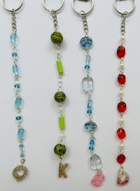 four keychains with beads and charms hanging from them