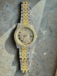 a gold and diamond watch on a concrete surface