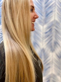 a woman with long blonde hair in front of a blue wall