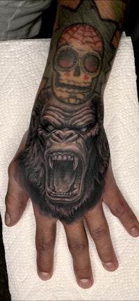 a hand with a gorilla tattoo on it