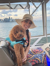 a woman sitting on a boat with her dog