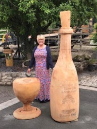 a woman standing next to a wooden wine bottle