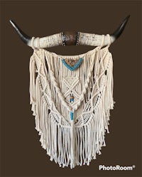 a macrame wall hanging with horns and turquoise beads