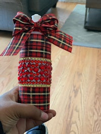 a person holding a red and black plaid bottle with a bow