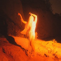 a woman in a white dress standing on a rock at night
