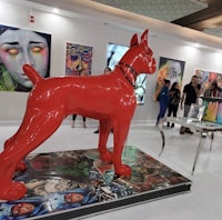 a red sculpture of a dog is on display in an art gallery