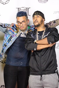 two men standing next to each other on a red carpet