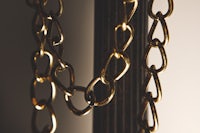a close up of a gold chain hanging from a lamp