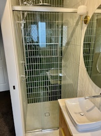a bathroom with a green tiled shower stall and sink