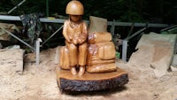 a wooden statue of a soldier sitting on a log