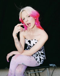a woman with pink hair sitting on a chair