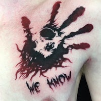 a man's chest tattoo with a hand with blood on it
