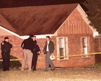 a group of police officers stand outside a house at night