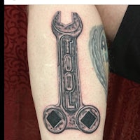 a tattoo of a wrench on a person's leg